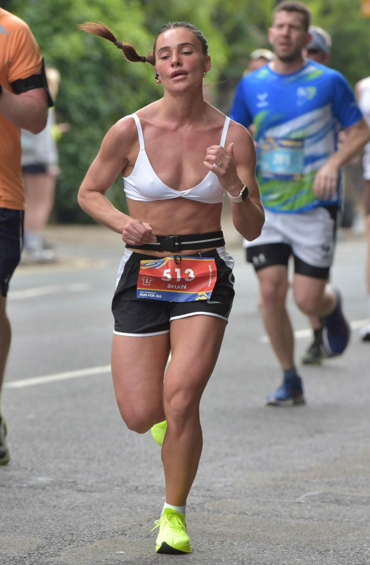The coach is stretching. Smiling and looking sideways.