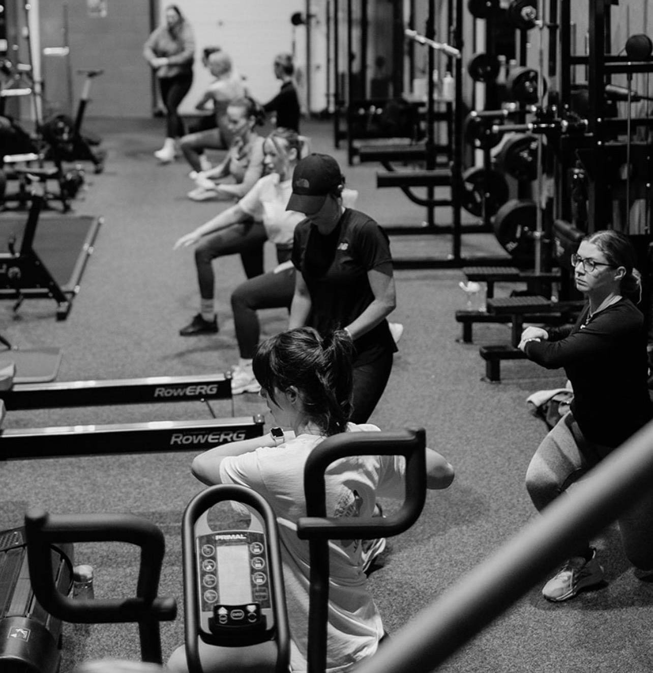 The coach is stretching up. Smiling and looking into the camera.